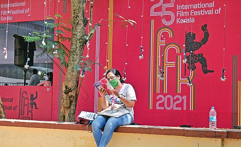 A delegate reading on the premises of Tagore Theatre, the main venue of International Film Festival of Kerala, in Thiruvananthapuram