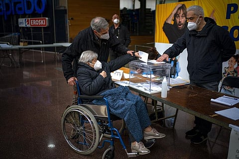 A woman casts her vote for the regional Catalan election at a polling station set up in a market in Barcelona, Spain, Sunday, Feb. 14, 2021. (Photo | AP)