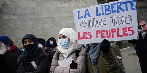 An activist holds a placard reading 'Freedom guides all people' during a gathering in Paris. (Photo | AP)