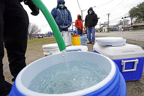 A water bucket is filled as others wait in near freezing temperatures to use a hose from public park spigot (Photo | AP)