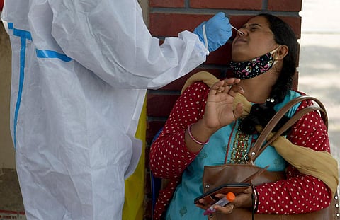 A health worker collects a swab sample from a traveller at a KSRTC bus stand in Bengaluru. (Photo | Meghana Sastry, EPS)