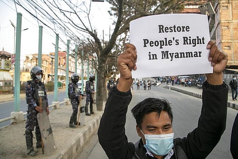 Policemen stand guard as a Nepalese Civil society activist holds a placard reacting to the developments in Myanmar during a protest in Kathmandu. (Photo | AP)
