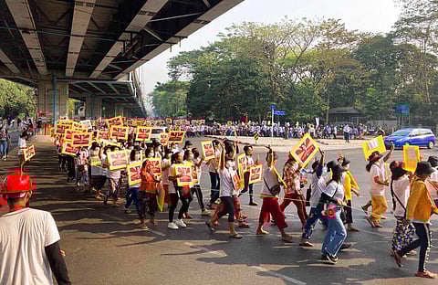 Anti-coup protesters holding posters of deposed Myanmar leader Aung San Suu Kyi march outside the Hledan Centre in Yangon, Myanmar. (Photo | AP)