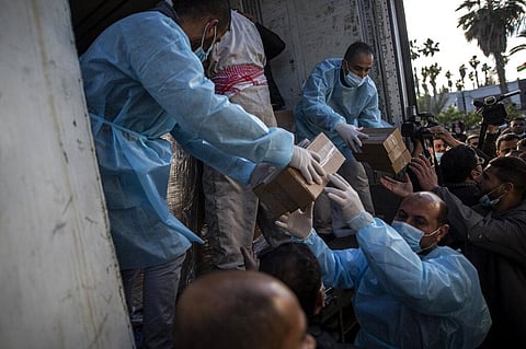 Palestinian workers unload a truck from 20,000 doses of Russian-made Sputnik V vaccine upon its arrival to Gaza Strip, at the Rafah crossing border with Egypt. (Photo | AP)