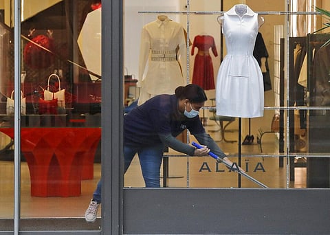 A woman wearing a face covering due to the COVID-19 pandemic cleans inside a shop during lockdown in London, Wednesday, Feb. 17, 2021. (Photo | AP)