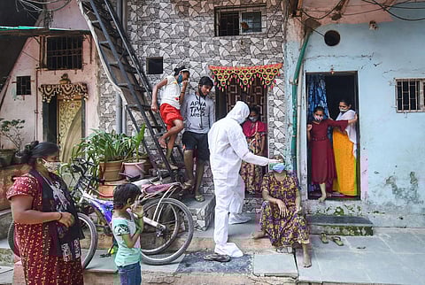 A BMC health worker wearing protective gear takes a swab sample of a woman for the COVID-19 test at Dharavi, in Mumbai. (Photo | PTI)