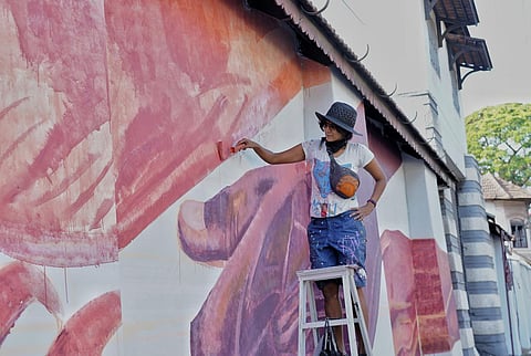 Artist Anpu Varkey painting a mural as part of the exhibition