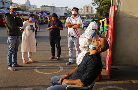 A health worker takes a nasal swab sample to test for COVID-19 outside a railway station in Ahmedabad, India. (File Photo | AP)
