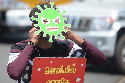 A man wears a mask depicting a coronavirus and a placard as a punishment enforce by the police. (Photo| AFP)