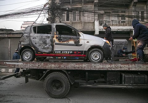 Nepalese policemen tow a damaged taxi on a truck after it was burned by demonstrators during general strike in Kathmandu. (Photo | AP)