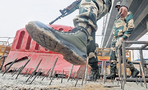 Paramilitary personnel tread carefully to avoid iron nails put up at Tikri border, on Thursday | Shekhar Yadav