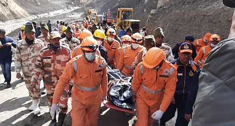 NDRF personnel carry a mortal remains of a victim near Raini village after the massive flood in the Dhauli Ganga river, in Chamoli district of Uttarakhand, on Tuesday. (Photo | Shekhar Yadav/EPS)
