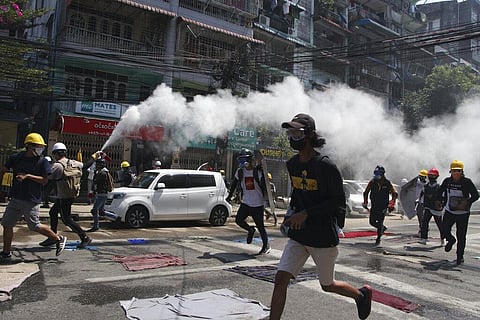 An anti-coup protester discharges a fire extinguisher to counter the impact of the tear gas fired by police during a demonstration in Yangon, Myanmar. (File Photo | AP)