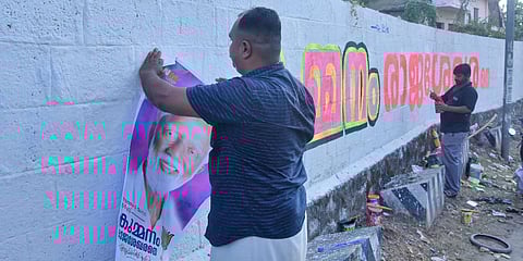 BJP workers paint the wall and stick posters of BJP candidate from Nemom Kummanam Rajasekharan, at Jagathy in Thiruvananthapuram. (Photo| BP Deepu, EPS)