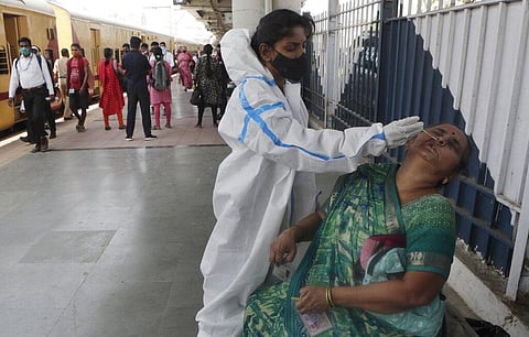 A health worker collects nasal swab of a passenger for COVID-19 test at a long distance train station in Mumbai. (Photo | AP)