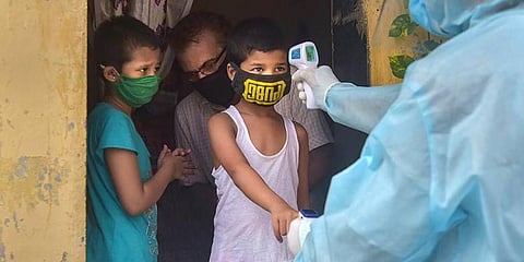 Volunteers carry out thermal testing for children in a slum area. (Photo | PTI)