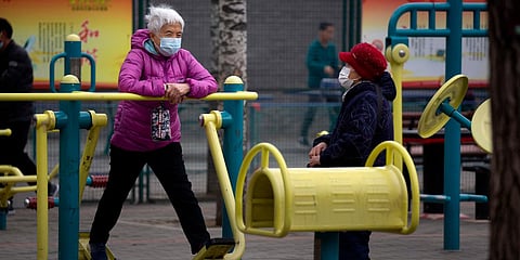 A woman wearing a face mask to protect against the coronavirus uses an exercise machine at a public park in Beijing. (File photo| AP)
