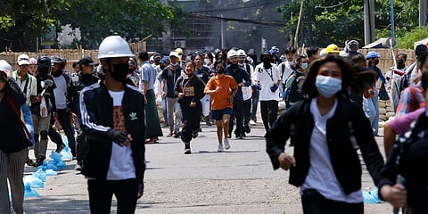 Anti-coup protesters abandon their makeshift barricade and run as policemen charge in Yangon. (File photo| AP)