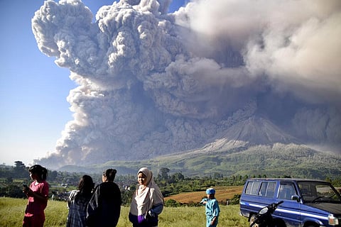 People watch as Mount Sinabung spews volcanic material during an eruption in Karo, North Sumatra, Indonesia. (Photo | AP)