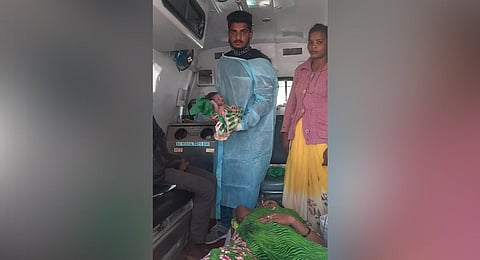 A 108 ambulance staffer holds a newborn baby right after its delivery.