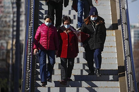 People wearing face masks to help curb the spread of the coronavirus walk down a pedestrian overhead bridge in Beijing (Photo | AP)