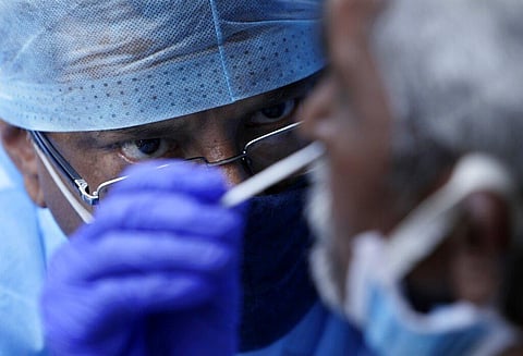 A health worker takes a nasal swab sample to test for COVID-19 at a market place. (Photo | AP)