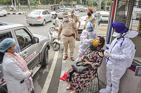 Health workers collect swab sample from a woman, who was allegedly violating COVID-19 norms, in Patiala. (Photo | PTI)