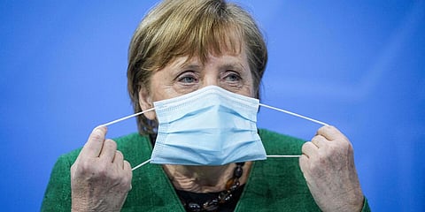 German Chancellor Angela Merkel removes her mask at the start of a press conference in the Chancellor's Office in Berlin. (Photo| AP)