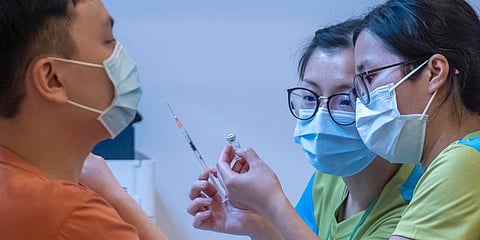 Health workers look at a vial and a syringe while administering a dose of the Sinovac Biotech COVID-19 vaccine at a community vaccination center in Hong Kong. (Photo | AP)