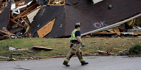 A firefighter surveys damage to a house after a tornado touched down. (Photo | AP)