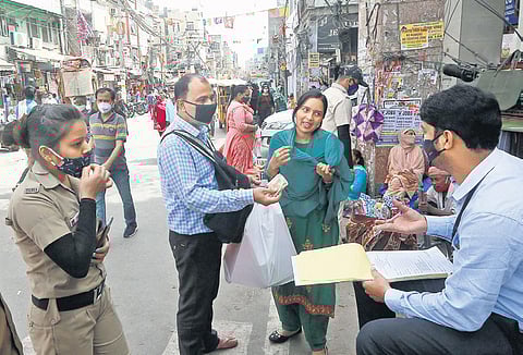 A Delhi civil defence personnel issues a challan to a woman for not wearing a face mask in New Delhi on Thursday | Shekhar Yadav