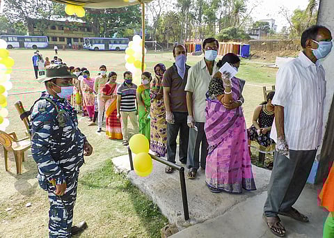 A paramilitary jawan guards as people wait in a queue to cast their votes during the first phase of West Bengal Assembly polls, at Chhara in Bankura, Saturday. (Photo | PTI)