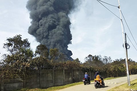 Motorists ride past as thick smoke billows from a fire that razes through Pertamina Balongan Refinery in Indramayu, West Java, Indonesia. (Photo | AP)