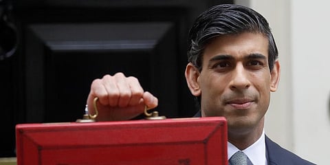 Britain's Chancellor Rishi Sunak stands with his red briefcase in front of 11 Downing Street in London. (Photo | AP)