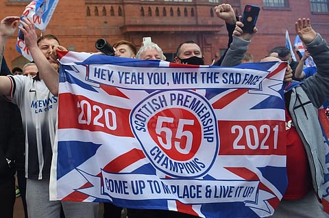 Rangers fans celebrate with flags outside Ibrox Stadium, home of Rangers Football Club, in Glasgow on March 7, 2021 after their 1st Scottish Premiership title for 10 years was confirmed. (Photo | AFP)