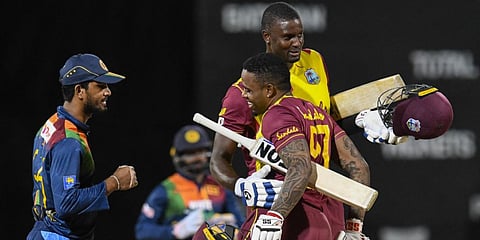 Dinesh Chandimal (L) of Sri Lanka watch as Fabian Allen (C) and Jason Holder (R) of West Indies celebrate winning the 3rd T20 match at Coolidge Cricket Ground in Osbourn