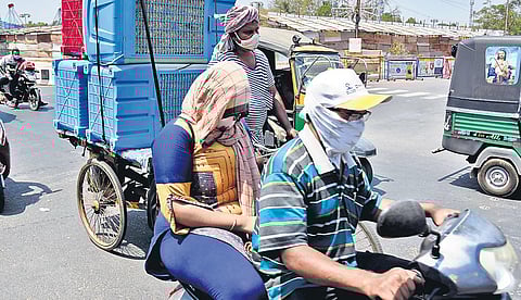 Commuters cover their faces to protect themselves from the scorching sun on MG Road in Vijayawada on Wednesday | P Ravindra Babu