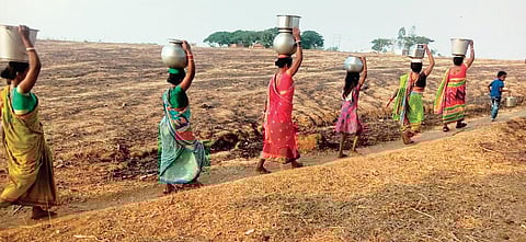 Women and kids carrying water in a village