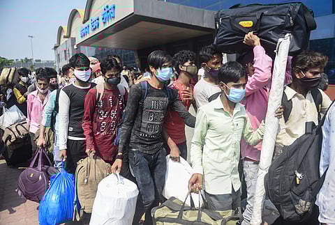 Passengers stand outside the Lokmanya Tilak Terminus to board outstation trains, amid the ongoing spike in COVID-19 cases in Mumbai, Wednesday. (Photo | PTI)