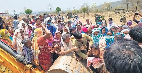 Tribals try to stop an earthmover that was being used by the officials to remove their deeksha tent, near Thummalacheruvu in Aswapuram mandal on Friday