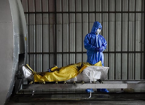A family member, wearing a protective suit, performs last rites of a person who died of COVID-19, at Nigam Bodh Ghat crematorium in New Delhi. (Photo | PTI)