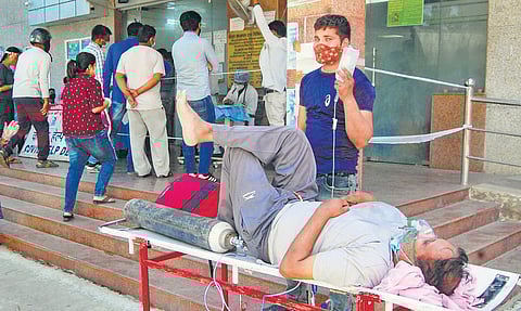 A patient on oxygen and drips on a stretcher, apparently due to the lack of Covid beds, receiving primary care outside the Kanpur LLR Hospital. (Photo | PTI)