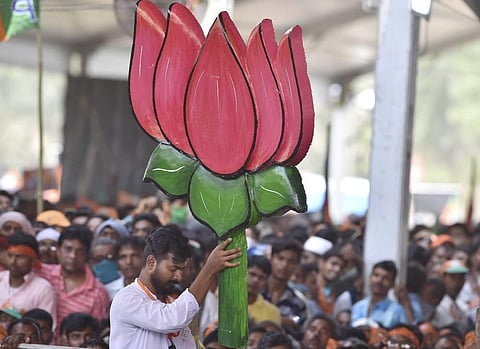 A BJP party activist, holding a cut out of the party symbol, attends an election campaign rally of Prime Minister Narendra Modi. (Photo | PTI)