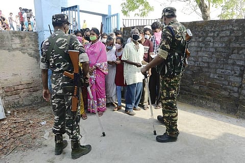 Security personnel stand guard as citizens wait to cast their vote during the second phase of West Bengal assembly polls. (Photo | PTI)