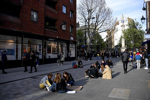 People sit on the pavement in London as shops, gyms, hairdressers, restaurant patios and beer gardens reopened after months of lockdown. (Photo | AP)