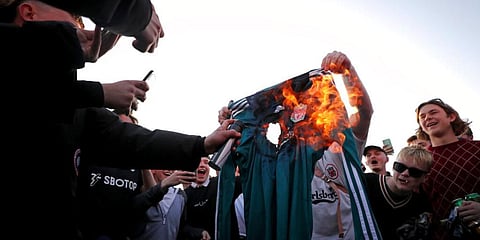 Fans burn Liverpool replica shirt against club's decision to be included amongst the clubs attempting to form European Super League. (Photo | AP)