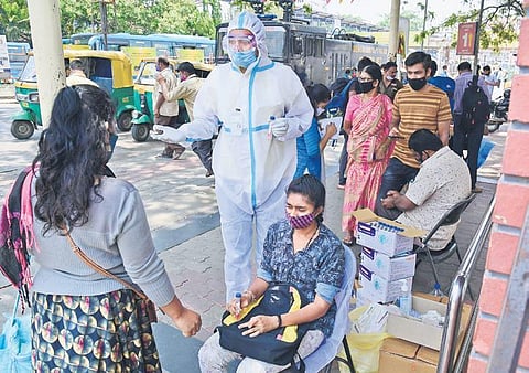 A healthcare worker prepares to collect a swab sample from a passenger at the Kempegowda Bus Station in Bengaluru on Sunday. (Photo | Shriram BN/EPS)