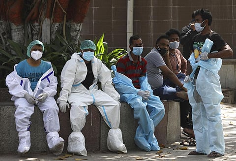 Health workers rest in between cremating COVID-19 victims in New Delhi. (Photo | AP)