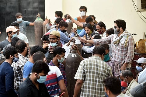 Family members of COVID-19 patients wait to fill their empty cylinders with medical oxygen outside an oxygen filling center, as demand for the gas rises. (Photo | PTI)