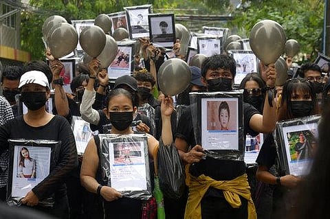 Anti-coup protesters holding pictures of those who died during a protest against the military offer prayers for them, in Yangon, Myanmar (File Photo | AP)